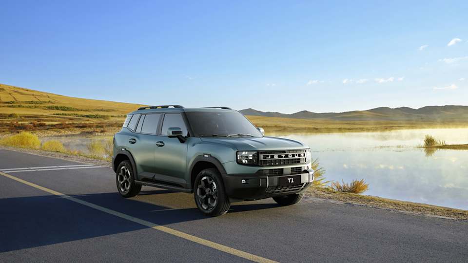 Jetour T1 SUV in matte green, front three-quarter view, parked on a road beside a misty lake and grassy hills