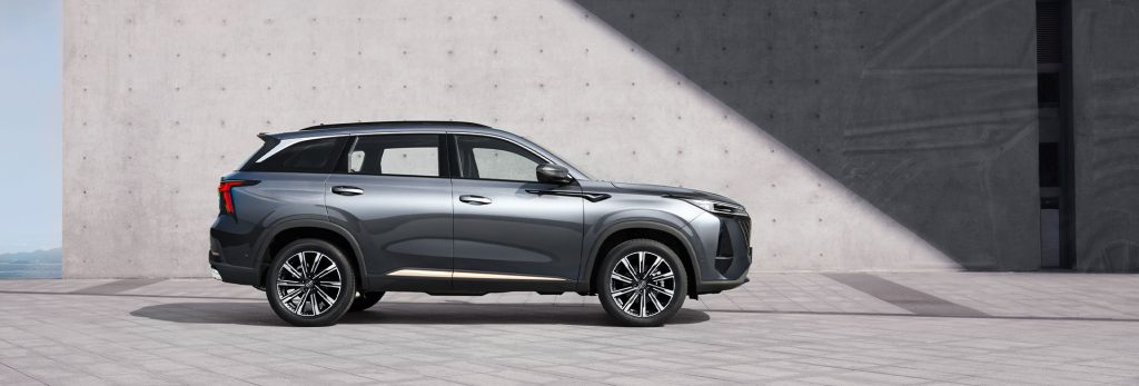 سيارة Changan CS75 Plus رمادية من الجانب على ساحة إسمنتية أمام جدار خرساني حديث
